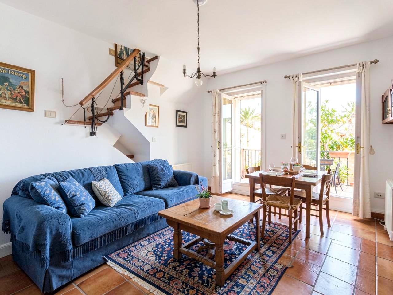 Woonkamer met blauwe bank en eethoek bij de terrasdeuren